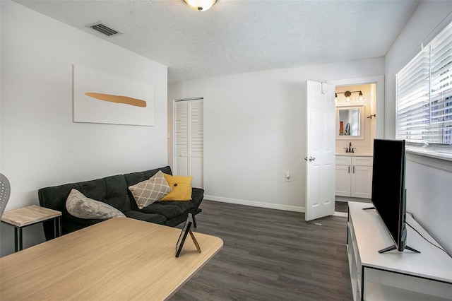 living room with sink, dark hardwood / wood-style flooring, and a textured ceiling