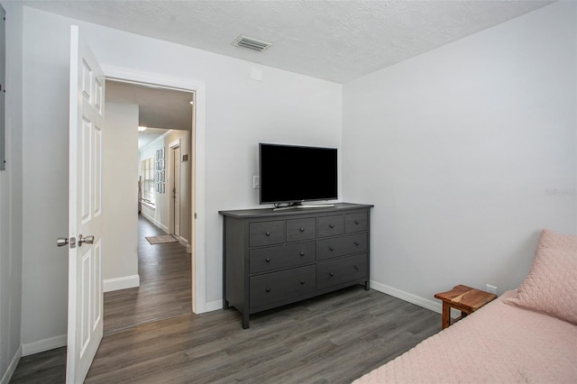 bedroom featuring a textured ceiling and dark hardwood / wood-style floors