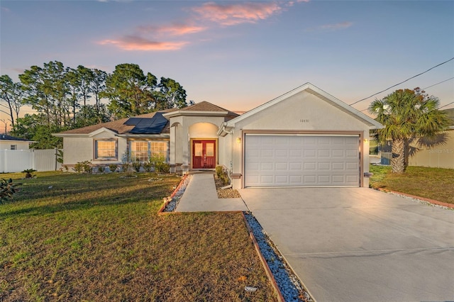 view of front of house with solar panels, a yard, and a garage