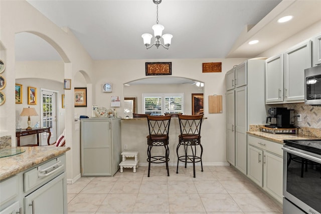 kitchen with stainless steel appliances, decorative light fixtures, decorative backsplash, and light stone countertops