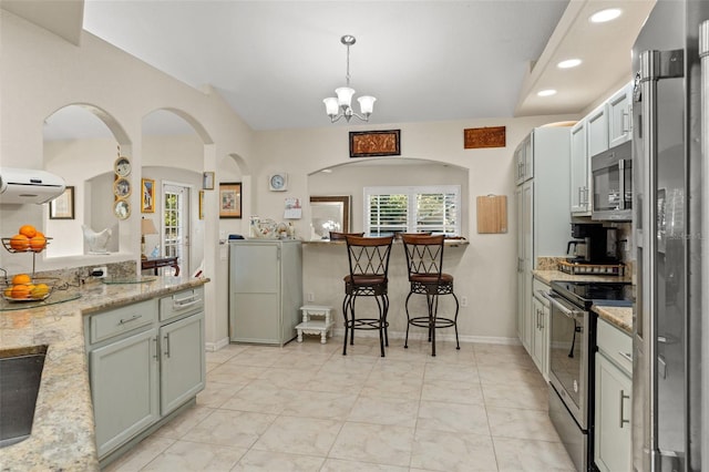 kitchen with light stone countertops, pendant lighting, stainless steel appliances, a notable chandelier, and sink