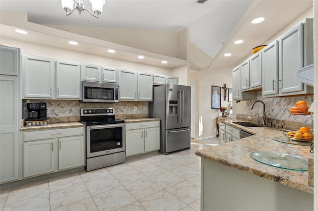 kitchen featuring vaulted ceiling, stainless steel appliances, a notable chandelier, backsplash, and sink