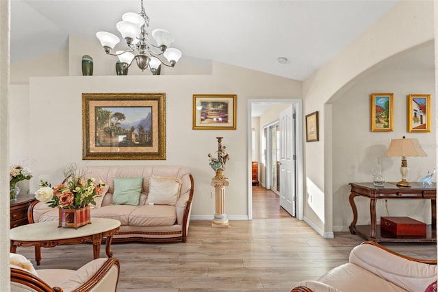 living room featuring a chandelier, vaulted ceiling, and light hardwood / wood-style flooring