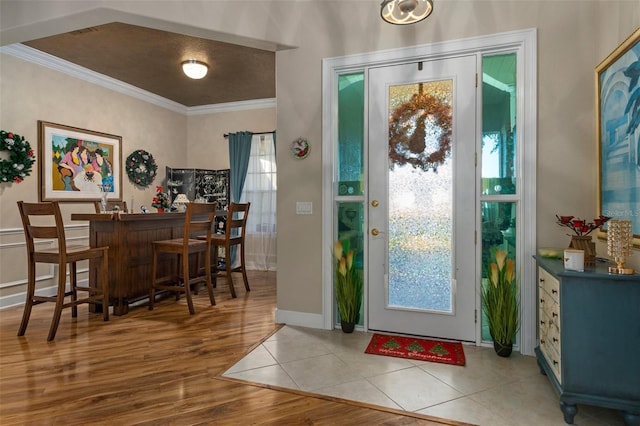 entryway featuring plenty of natural light, bar area, crown molding, and light tile patterned flooring