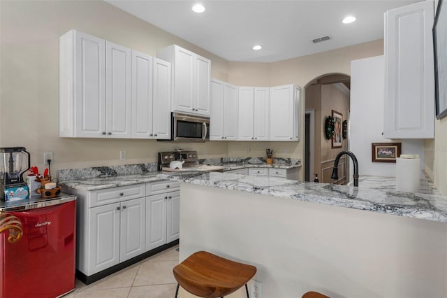 kitchen with white cabinets, appliances with stainless steel finishes, sink, light stone counters, and light tile patterned floors