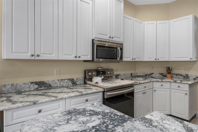 kitchen with light stone countertops, stainless steel appliances, and white cabinetry