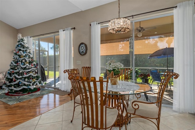 tiled dining area with ceiling fan with notable chandelier