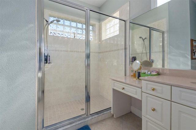 bathroom with walk in shower, vanity, and tile patterned flooring