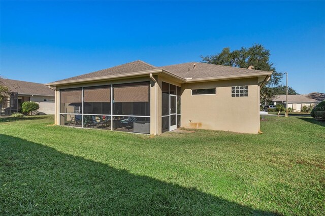 back of property featuring a yard and a sunroom