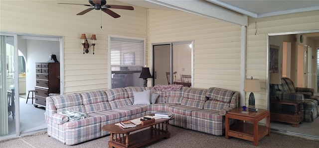 carpeted living room with wood walls and ceiling fan