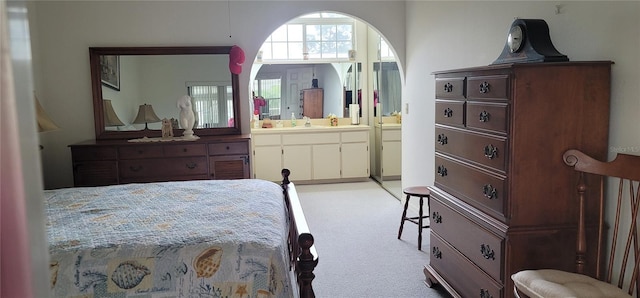 bedroom featuring sink, ensuite bathroom, and light carpet