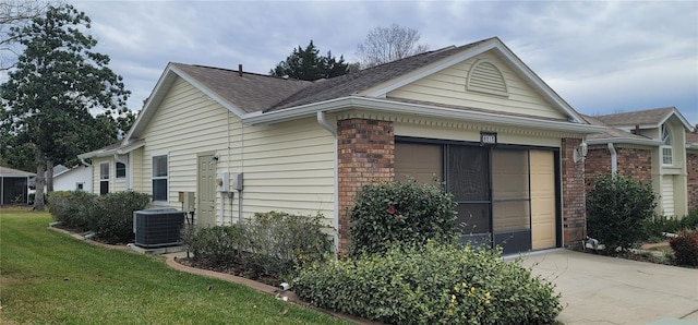 exterior space with a yard, central AC, and a garage