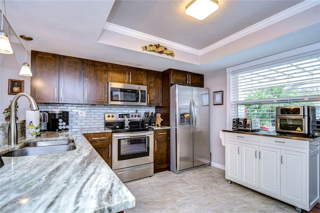 kitchen with stainless steel appliances, pendant lighting, light stone counters, a tray ceiling, and sink