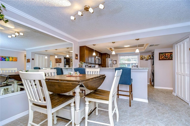 dining area with sink, a raised ceiling, crown molding, and a textured ceiling