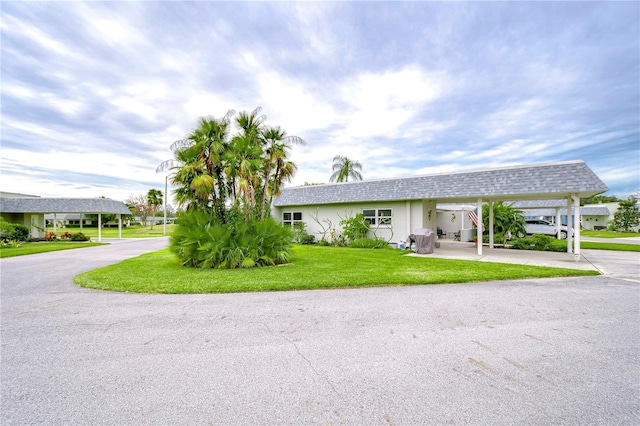 ranch-style house featuring a front lawn and a carport