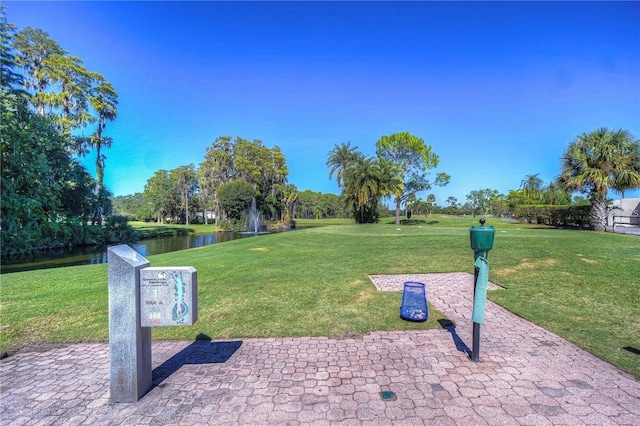 view of community with a patio, a yard, and a water view