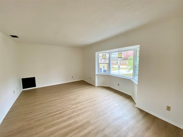 empty room featuring a textured ceiling and light wood-type flooring