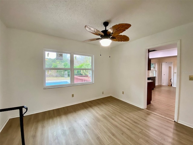 unfurnished room with wood-type flooring, a textured ceiling, and ceiling fan