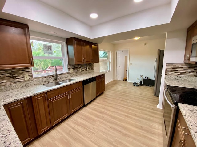 kitchen with light stone counters, stainless steel appliances, light wood-type flooring, and sink