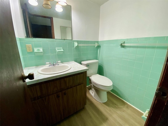 bathroom with toilet, vanity, tile walls, and hardwood / wood-style floors