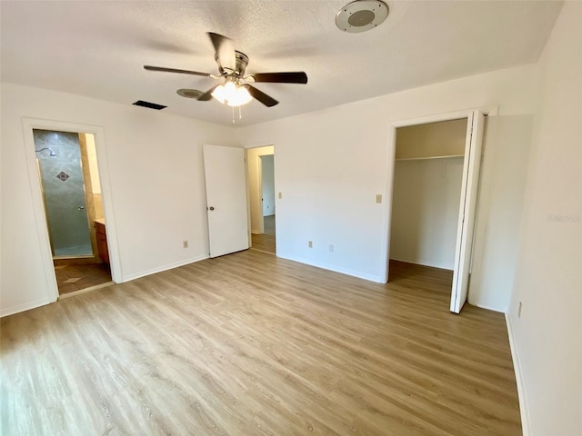 unfurnished bedroom with ceiling fan, light hardwood / wood-style floors, connected bathroom, and a textured ceiling