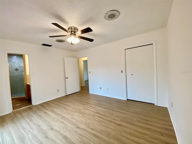 unfurnished bedroom featuring ensuite bathroom, a textured ceiling, ceiling fan, and light hardwood / wood-style floors