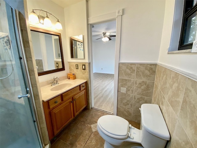 bathroom with toilet, a shower with door, ceiling fan, and vanity