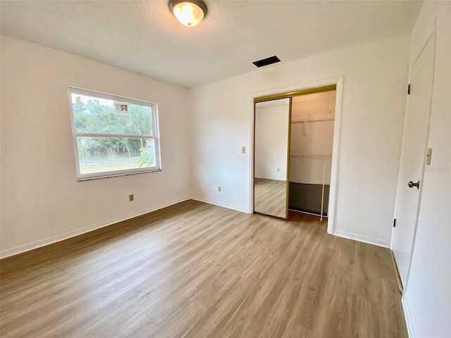 unfurnished bedroom with light hardwood / wood-style floors, a closet, and a textured ceiling