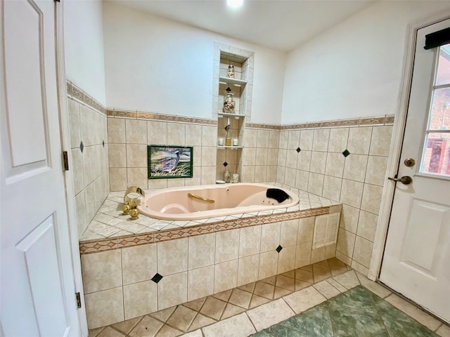 bathroom with a relaxing tiled tub, tile patterned flooring, and tile walls