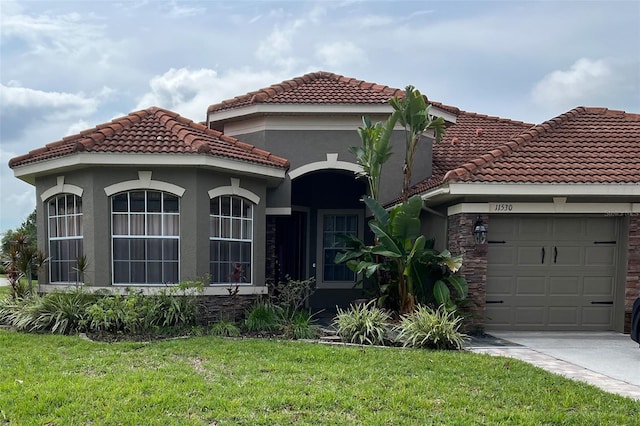 mediterranean / spanish home featuring a garage and a front lawn