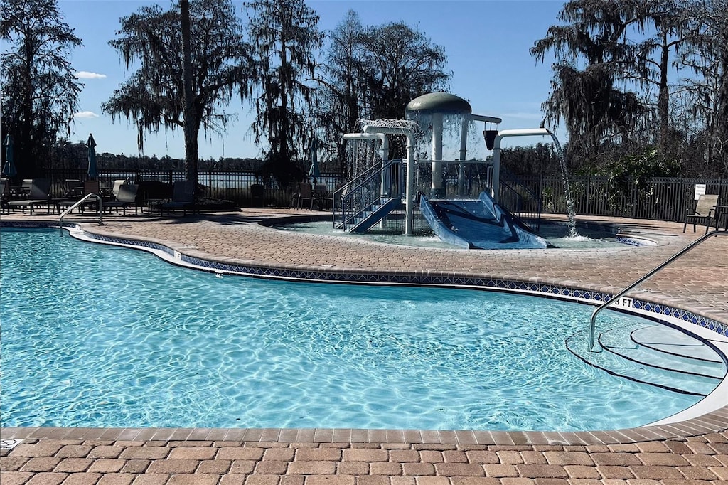 view of swimming pool featuring pool water feature and a playground