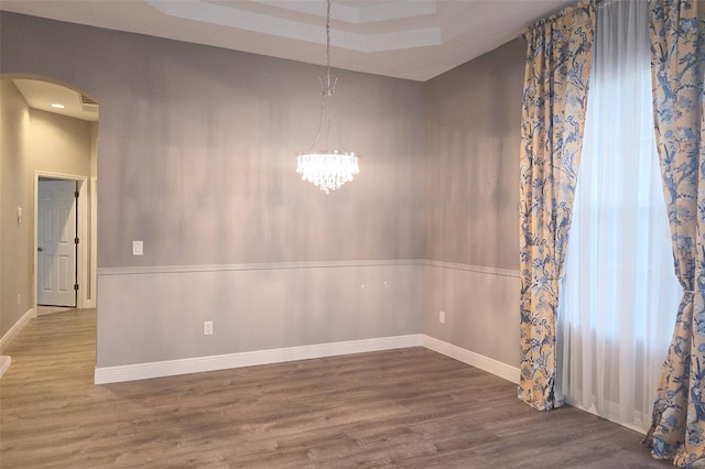 unfurnished dining area with hardwood / wood-style floors and a notable chandelier