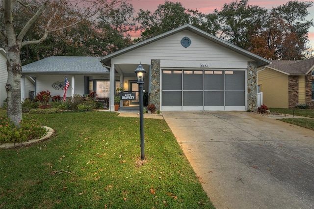 ranch-style house with a yard, covered porch, and a garage