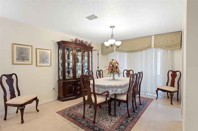 dining space featuring a textured ceiling, light tile patterned flooring, and a chandelier