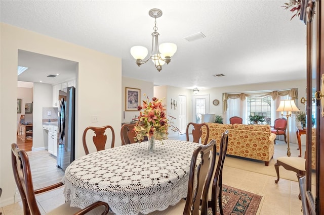 tiled dining area featuring an inviting chandelier and a textured ceiling