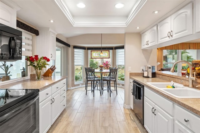 kitchen featuring a raised ceiling, white cabinetry, black appliances, and sink