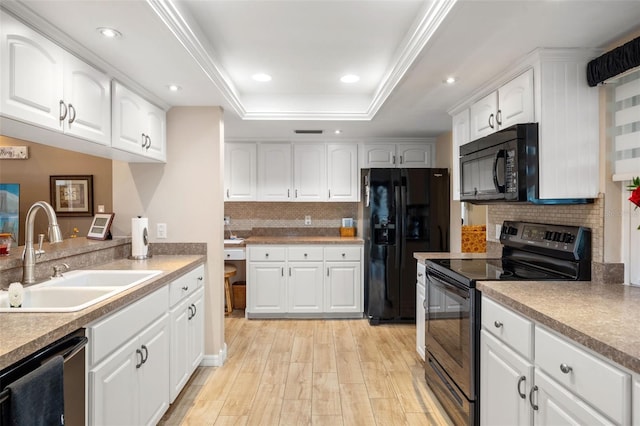 kitchen with sink, white cabinets, a raised ceiling, light wood-type flooring, and black appliances