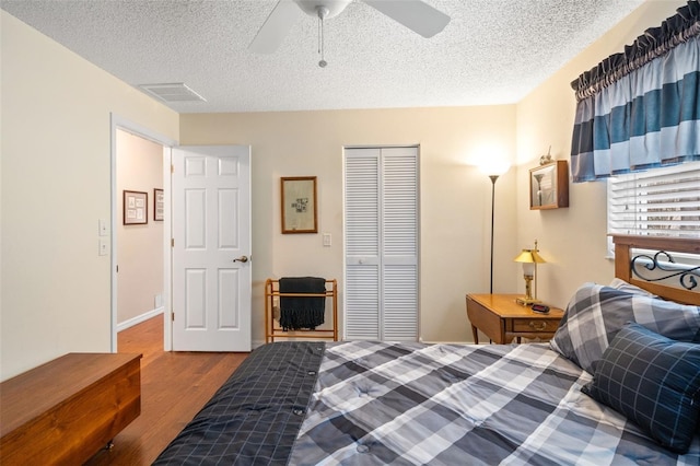 bedroom with a textured ceiling, ceiling fan, a closet, and hardwood / wood-style floors