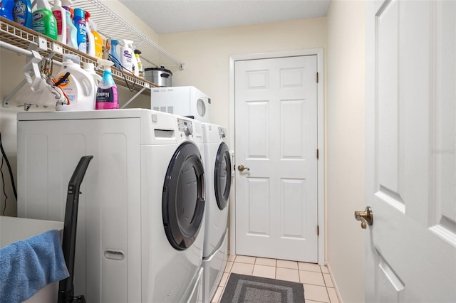 laundry area featuring washing machine and dryer and light tile patterned floors