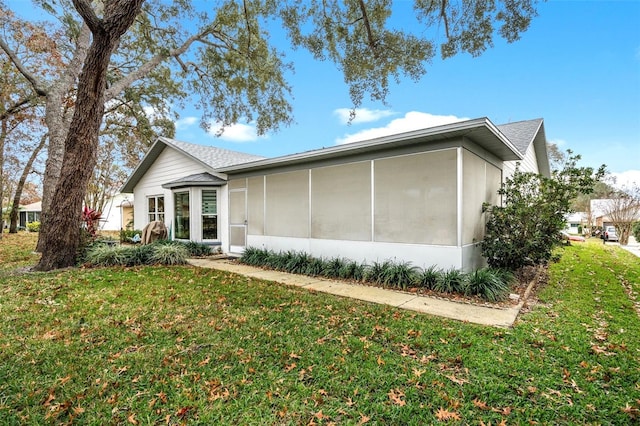 rear view of house featuring a yard and a sunroom