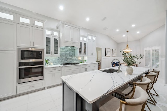 kitchen featuring sink, lofted ceiling, stainless steel appliances, and a kitchen island with sink