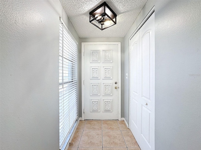 doorway to outside featuring a textured ceiling and light tile patterned flooring