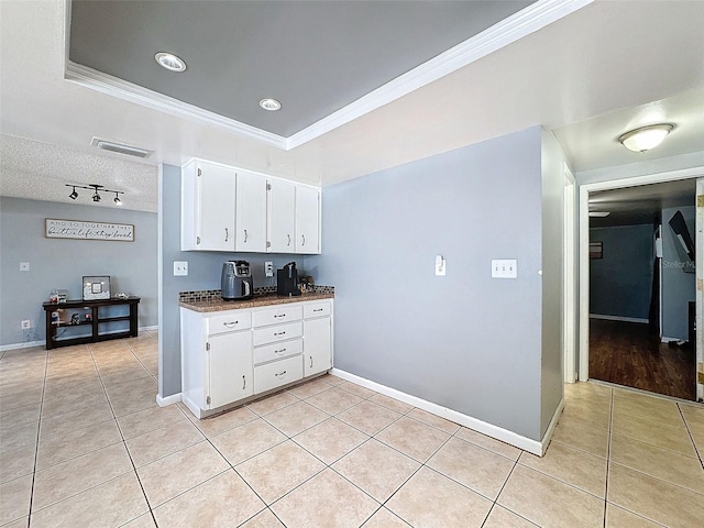 kitchen with light tile patterned floors, crown molding, a raised ceiling, and white cabinets