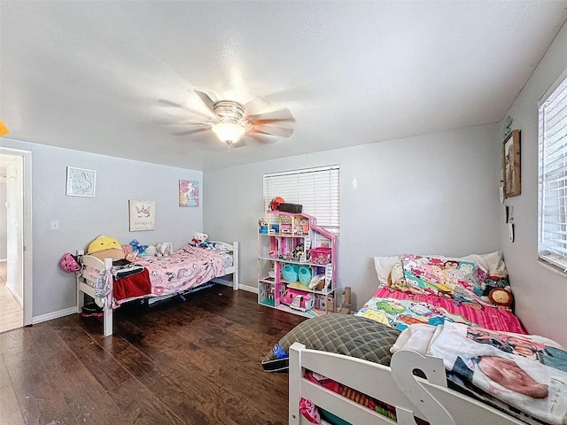 bedroom featuring ceiling fan, dark hardwood / wood-style flooring, and multiple windows