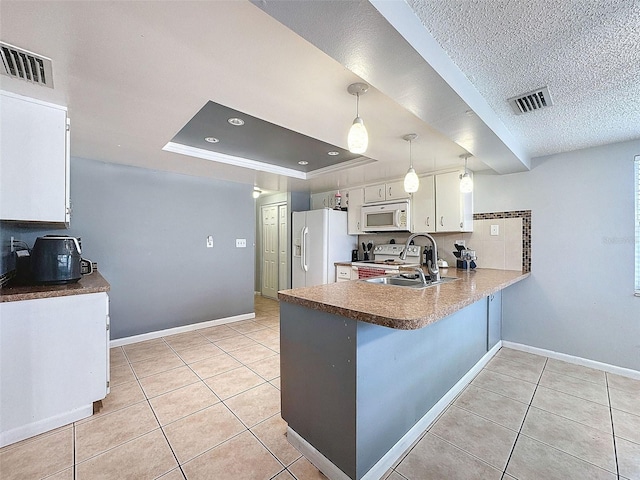 kitchen featuring white appliances, pendant lighting, white cabinetry, kitchen peninsula, and a tray ceiling