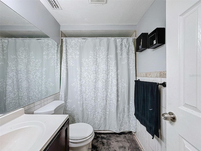 bathroom with a textured ceiling, toilet, and vanity