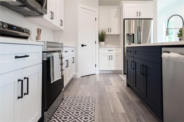 kitchen with sink, white cabinets, light hardwood / wood-style floors, and stainless steel appliances