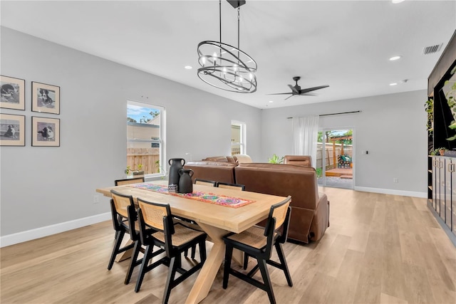 dining space with ceiling fan with notable chandelier and light hardwood / wood-style flooring