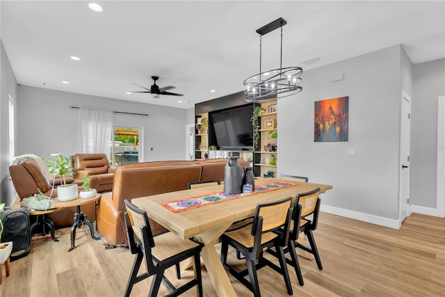 dining area with ceiling fan with notable chandelier and light hardwood / wood-style floors