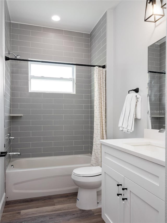 full bathroom with shower / bathtub combination with curtain, hardwood / wood-style floors, vanity, and toilet